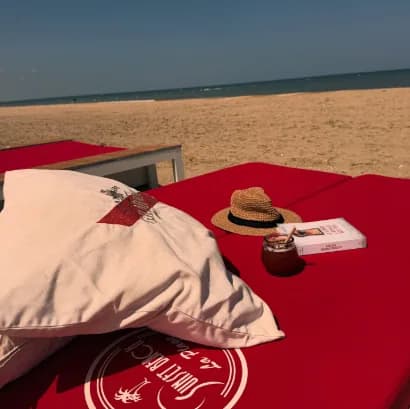 Plage privée du Sunset Beach : transat, chapeau de paille et sable face à la mer.