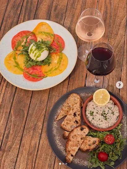 Carpaccio de tomates anciennes colorées et burrata crémeuse, servi en terrasse.
